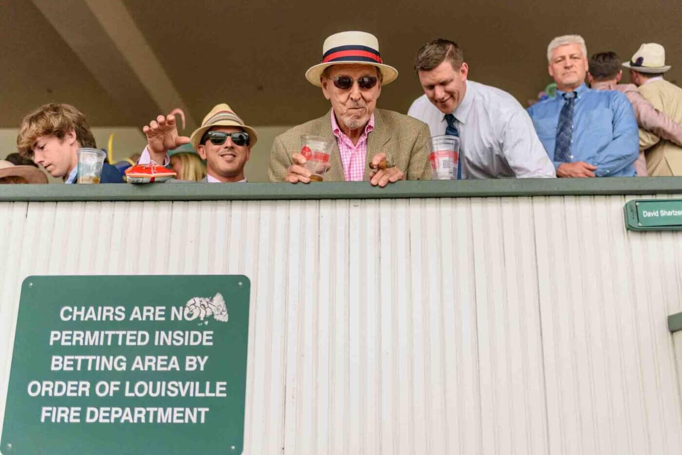 Soggy racing fans take shelter from the rain to make bets on the running of the 144th Kentucky Derby. May 5, 2018