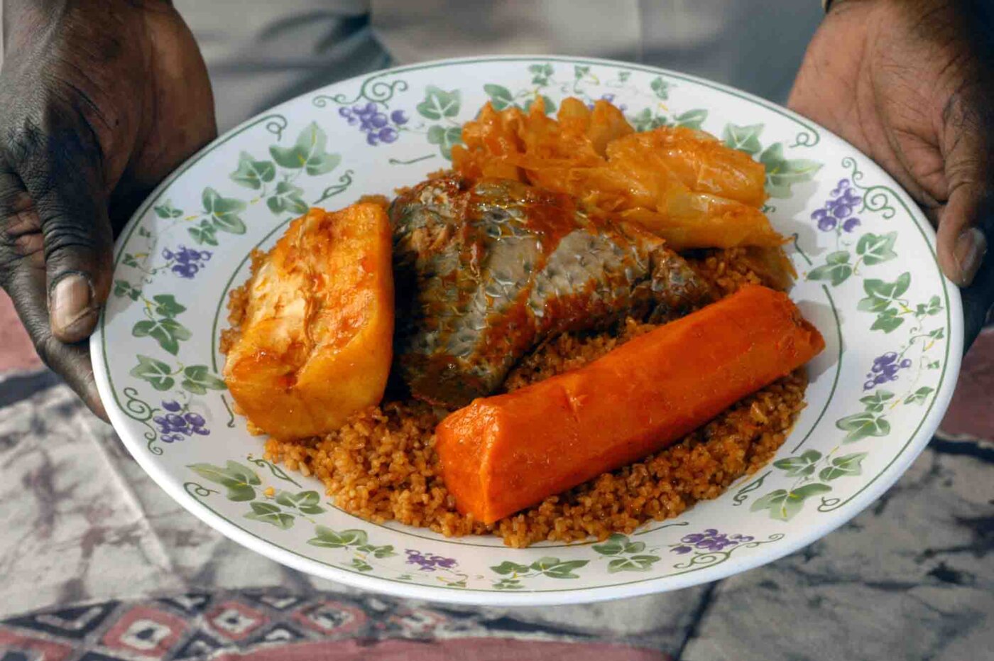 Chez Seneba: Oowner Fallou Sene holds Thiebu Jenn: Djdof rice cooked in a rich tomato sauce served with fish, carrots, cabbage, yucca and eggplant.